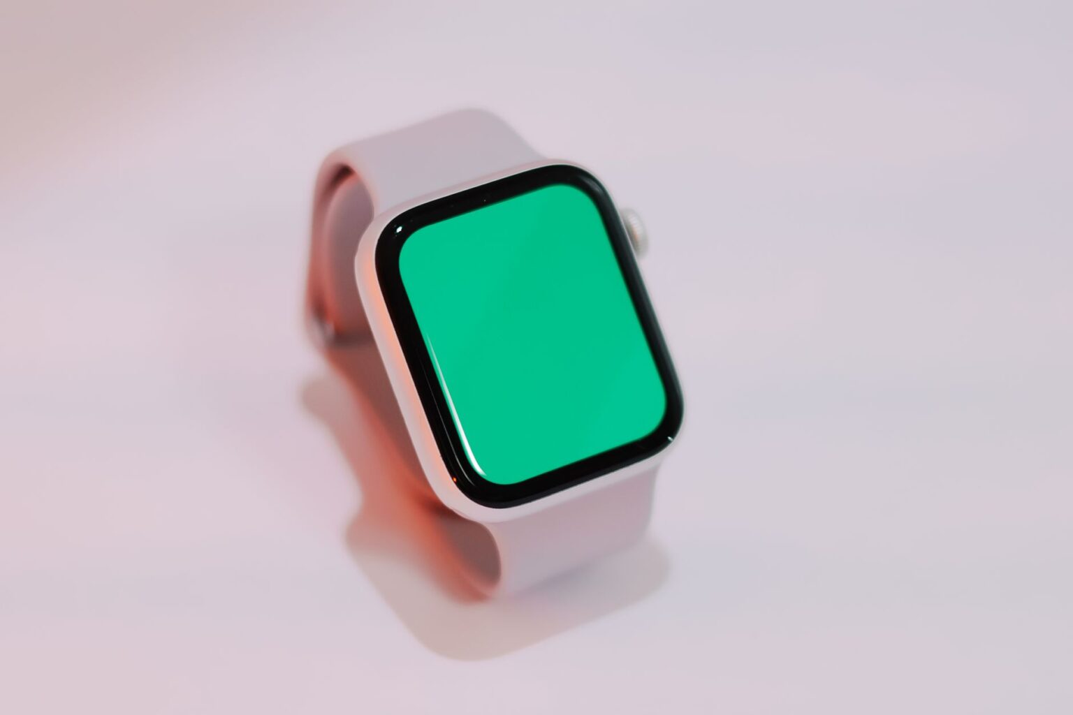 Nowoczesny smartwatch o jasnej kopercie z pustym zielonym ekranem spoczywa na jasnym tle